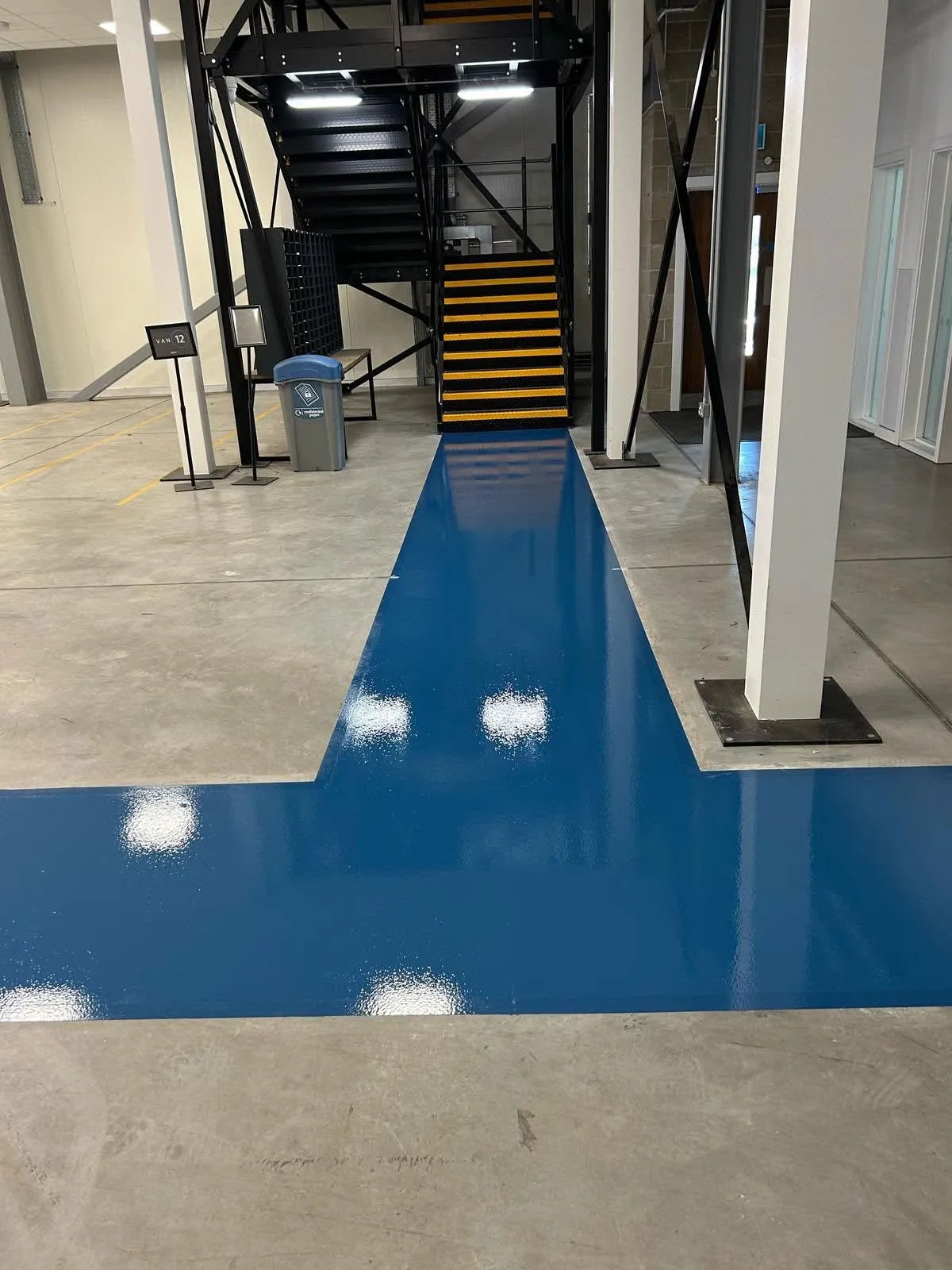 A blue resin walkway marked across a concrete warehouse floor