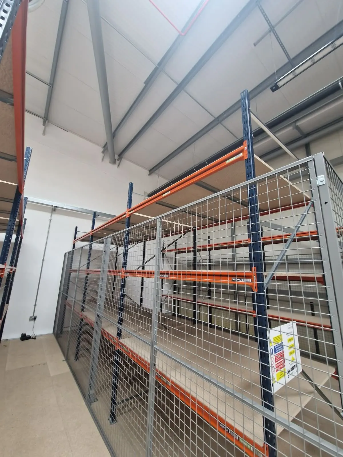 A galvanised mesh partition enclosing shelving bays